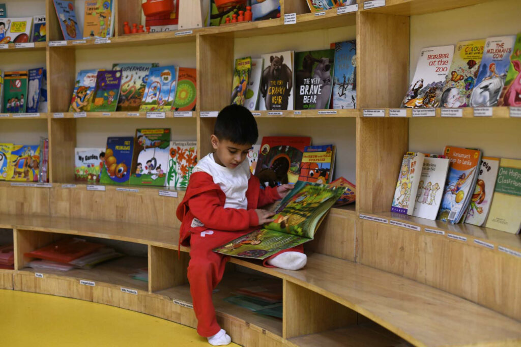 A kid reading a book in a library.
