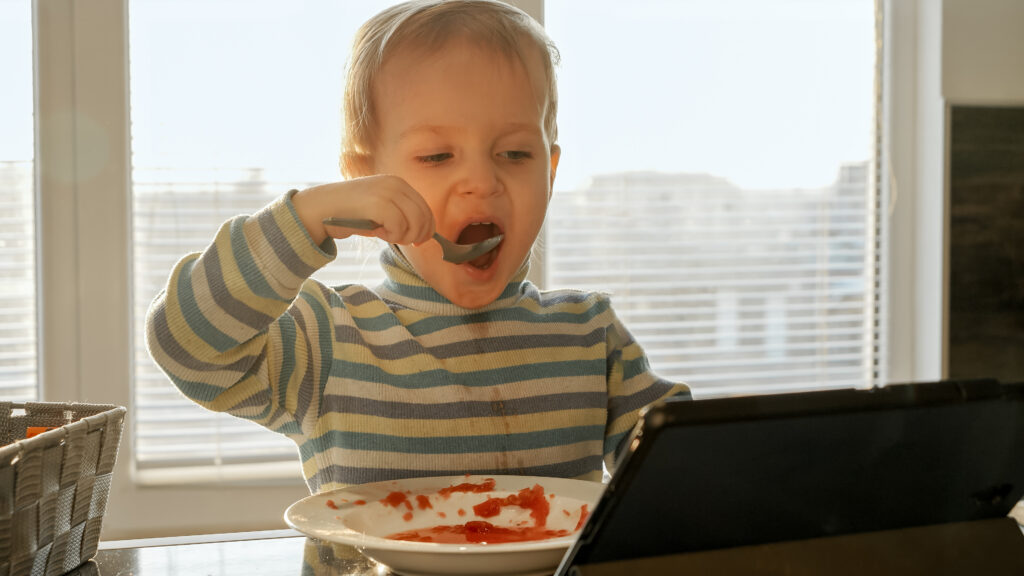 small-child-eating-lunch-while-watching-tablet-
